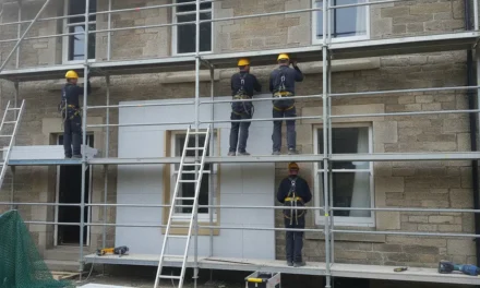 Façade d'une maison ancienne en pierre de taille en cours de rénovation avec échafaudage et ouvriers